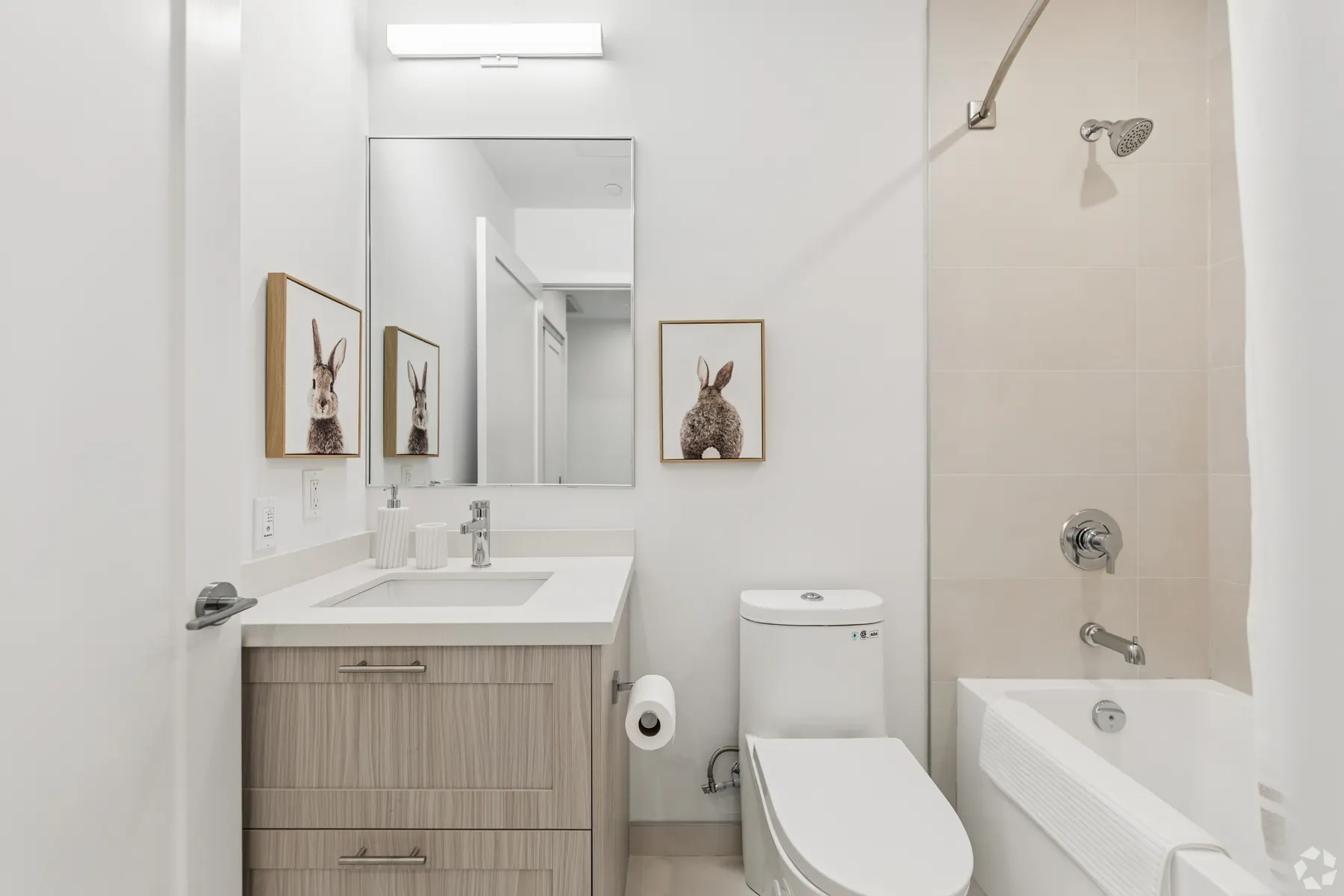 A suite bathroom: a white stone vanity under a mirror beside a tub and shower tiled in beige