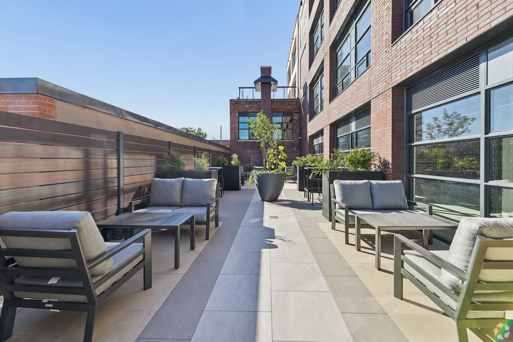 The barbecue terrace: outdoor sofas and low tables along a planted walkway beside the heritage brick