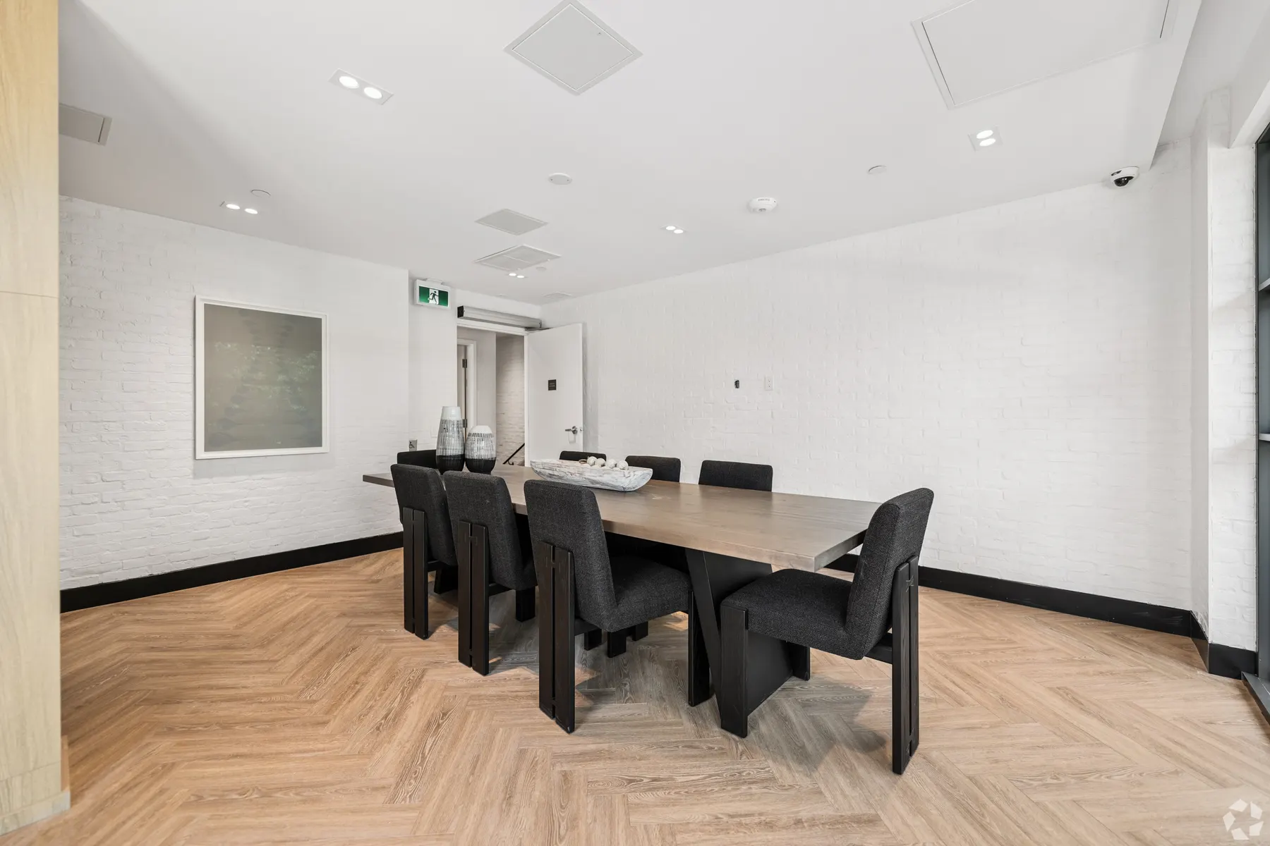 The second private dining room: a walnut table for eight on herringbone floors between white brick walls