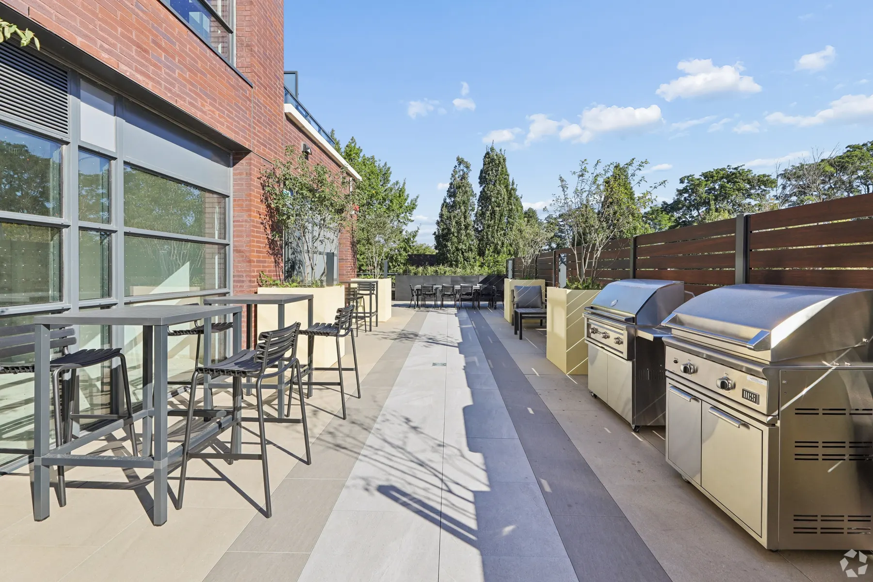 The barbecue terrace: bar height tables and stools along the glazing, two stainless barbecues at the far end